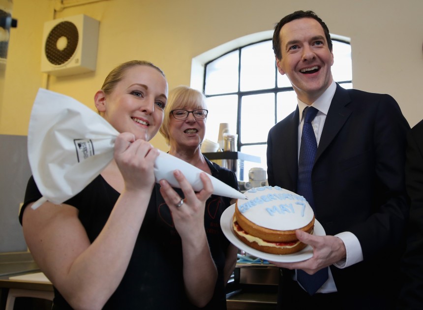 STOURBRIDGE, UNITED KINGDOM - APRIL 07:  Chancellor George Osborne holds a cake declaring 'Vote Conservative May 7' with cafe staff Sue Watkins and Sharon Henderson (L) during a visit to the Red Cone Cafe and visitor attraction on April 7, 2015 in Stourbridge, United Kingdom. Former Labour Prime Minister Tony Blair has joined the election campaign and has warned that a Conservative referendum on the European Union is an 'Unacceptable Gamble'.  (Photo by Christopher Furlong/Getty Images)