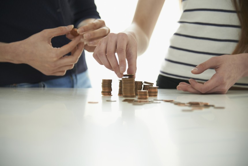 Midsection of mother and daughter stacking coins at table