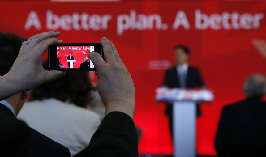 A member of the audience uses his phone to photograph Britain's Labour Party leader Ed Miliband gestures during a speech at a campaign event in Pensby northern England