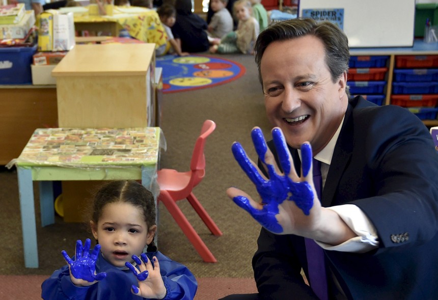 Britain's Prime Minister and leader of the Conservative party, David Cameron, (R) shows his hand after participating in a hand-printing session at the Advantage children's daycare nursery during a UK general election campaign event in Surbiton, south London on April 22, 2015. Britain goes to the polls to elect a new parliament on May 7.   AFP PHOTO / POOL / TOBY MELVILLE        (Photo credit should read TOBY MELVILLE/AFP/Getty Images)